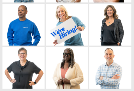 several portraits of different staff members. One of them is holding a poster with the words 
