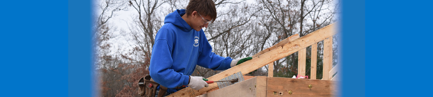 A Construction Trades student secures trusses on a structure