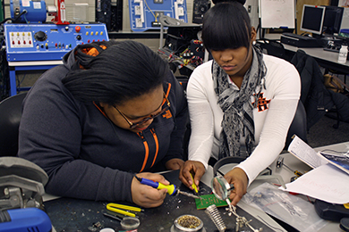 Two African American females working on a circuit board in the Electrical/Computer Technology class.