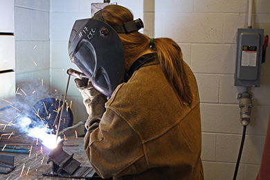 A female Welding student practices a weld.