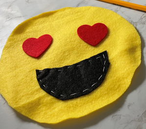 Handmade felt emoji with hearts for eyes and a smile