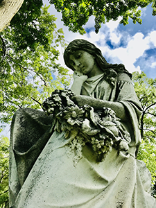 A green statue of an angel serenely looking down.