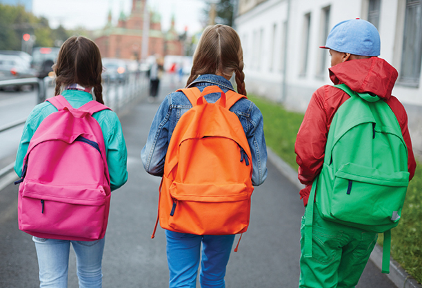 Three kids with colorful backpacks walking to school