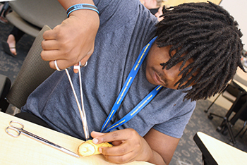 An Allied Heatlh student practices giving sutchers