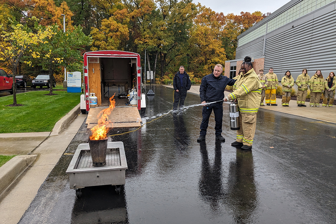 High school Criminal Justice students learn to use a fire extinguisher with help from fire fighters