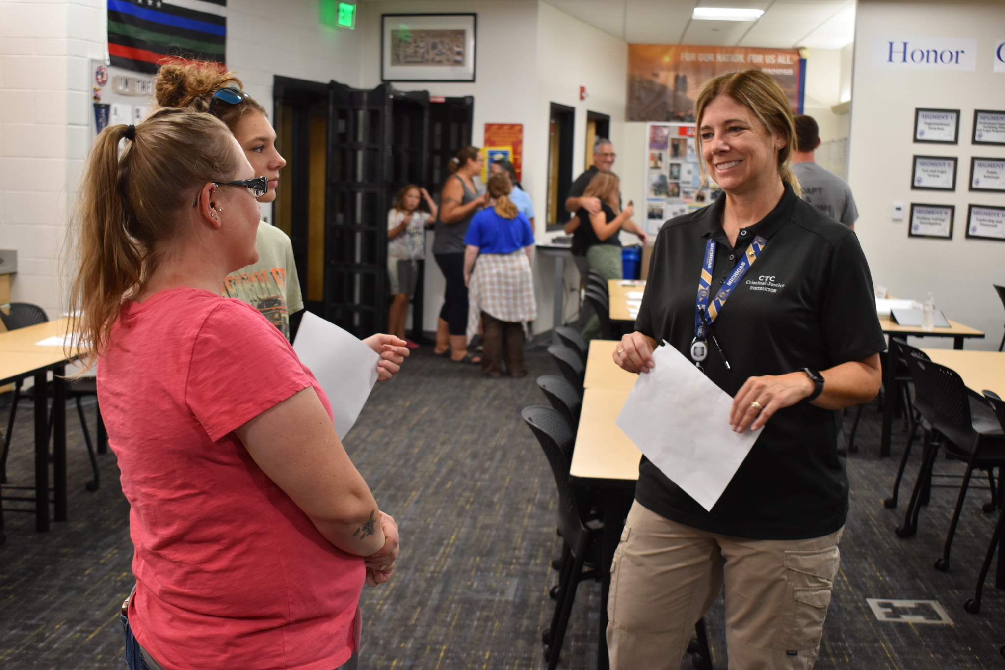 A smiling teacher speaking with a student and her parent