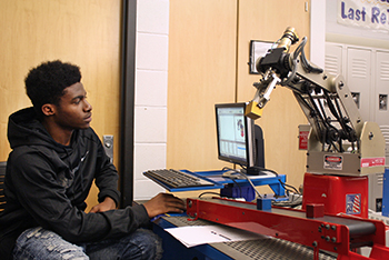 A student moves a robotic arm.