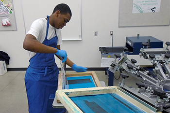 Graphic Production Technolgoies student screen printing.