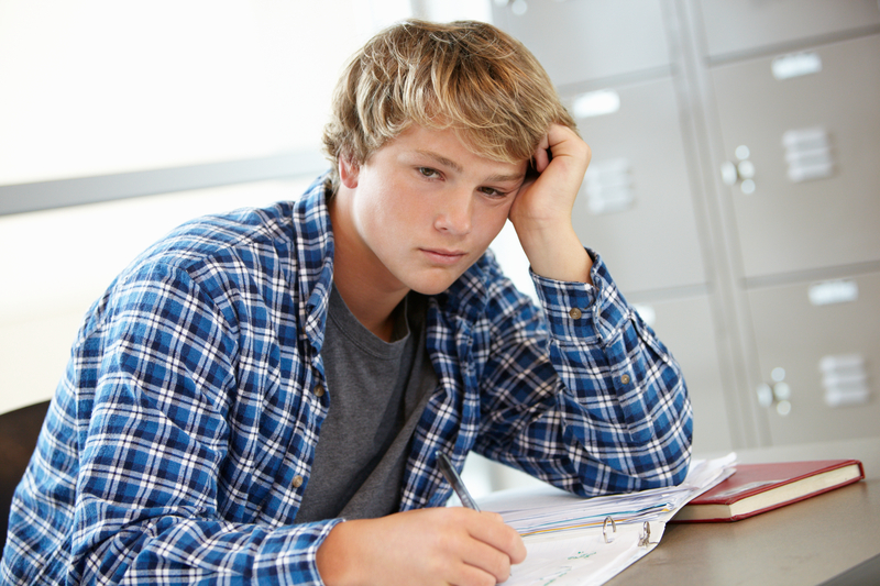 Teen boy sad while doing classwork
