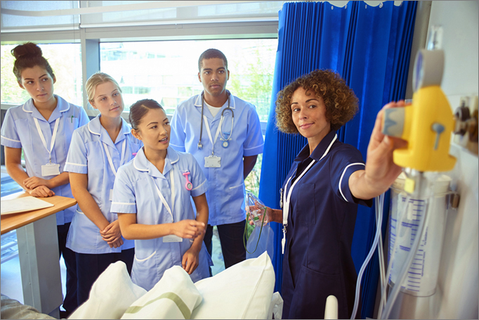 Group of health students with hospital employee examining medical equipment